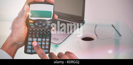 Hands of businessman using calculator  against laptop on desk with mug of coffee and glasses Stock Photo