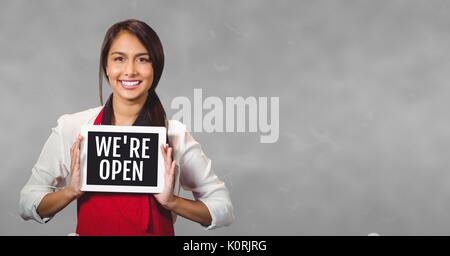 Digital composite of Business woman holding a tablet with we are open text Stock Photo