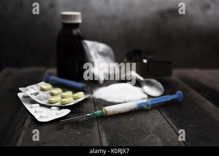 Hard drugs on dark table. A dark theme, drug use. Preparation of drugs, still life. Syringe with needle, spoon, tablets, lighter. Death. Stock Photo
