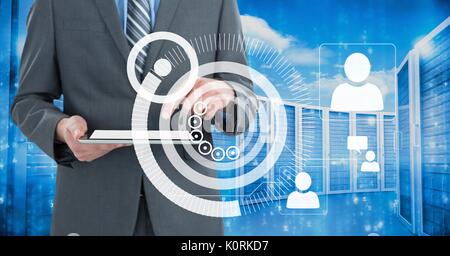 Digital composite of Business man holding a tablet and graphics in server room Stock Photo