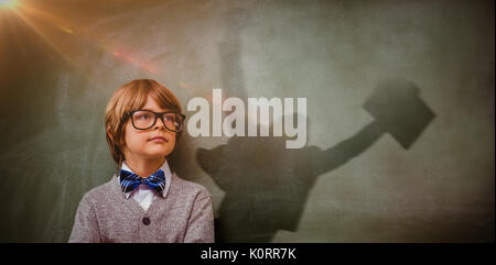 Businessman jumping while holding briefcase against boy with arms crossed looking up at blackboard Stock Photo