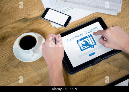 Tool with technical support text against cropped hands using tablet computer at table Stock Photo