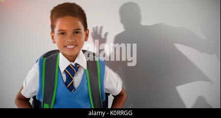 Graphic image of businessman running with breifcase against schoolboy in school uniform with school bag on white background Stock Photo