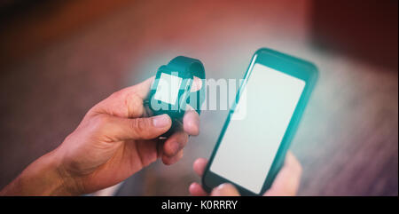 Cropped hands of man using smart watch and mobile phone in living room Stock Photo