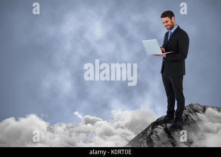 Businessman standing while using laptop computer against dark background Stock Photo