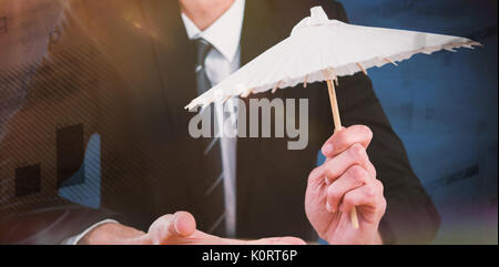 Businessman holding paper umbrella against blue background Stock Photo