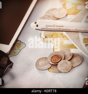 Close up of toy airplane with coins and tablet computer on map Stock Photo