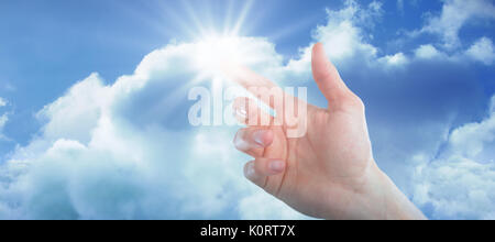 Hand of man pretending to touch an invisible screen against idyllic view of cloudscape against sky Stock Photo