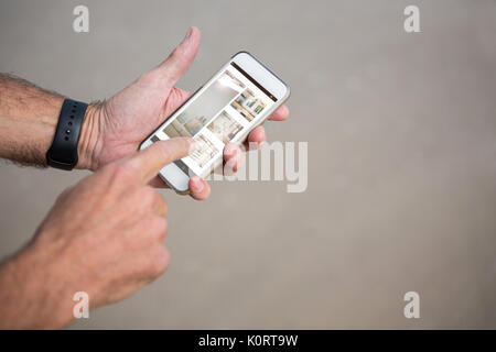 Sofa and window at home on mobile screen against cropped image of man using phone Stock Photo
