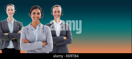 Business team wearing headsets and standing arms crossed against turquoise and orange background Stock Photo