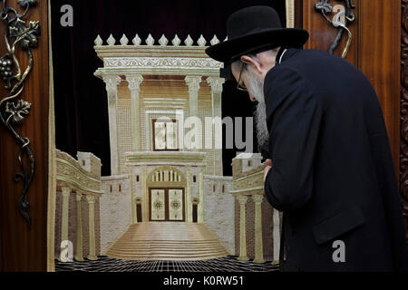 A Jewish worshiper praying next to a Torah Ark closet which contains the Jewish Torah scrolls decorated with a figure depicting the Biblical Jewish Temple inside the men's section of Wilson's Arch at the Western Wall compound in the old city. East Jerusalem, Israel Stock Photo