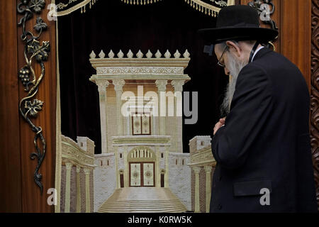 A Jewish worshiper praying next to a Torah Ark closet which contains the Jewish Torah scrolls decorated with a figure depicting the Biblical Jewish Temple inside the men's section of Wilson's Arch at the Western Wall compound in the old city. East Jerusalem, Israel Stock Photo