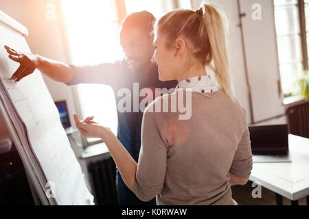 Young handsome designer presenting his work to female colleague Stock Photo