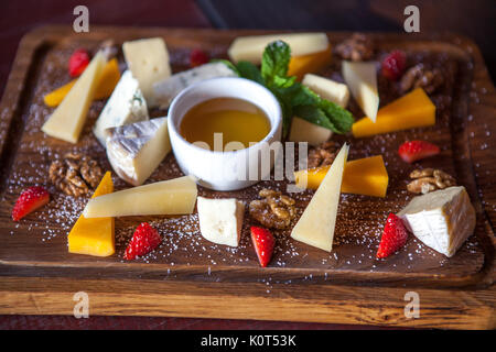 various cheeses with nuts and berries on a wooden Board Stock Photo