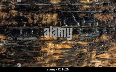 Ashes of partly burned wood board damaged by fire Stock Photo
