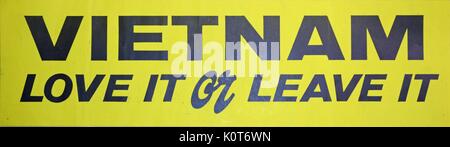 A Vietnam War era bumpersticker that has a yellow background and black lettering that reads 'Vietname love it or leave it'. 1970. Stock Photo