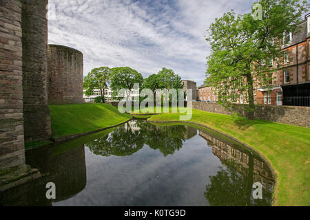 View, from historic castle, of town of Rothesay with buildings & castle walls reflected in water of moat under blue sky on island of Bute, Scotland Stock Photo