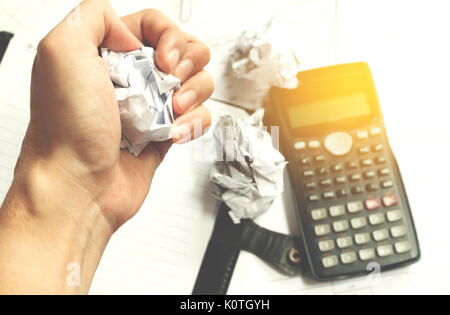 Businessman sitting at desk in a little office or home mad at work, ripping documents with frustrated hand expression. Throwing around scraps of paper Stock Photo