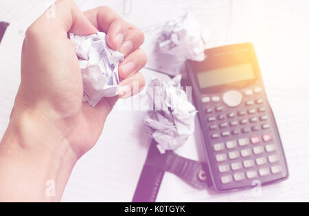 Businessman sitting at desk in a little office or home mad at work, ripping documents with frustrated hand expression. Throwing around scraps of paper Stock Photo