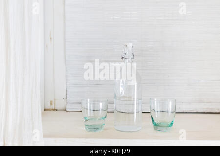 One transparent glass bottle and two cup for water isolated on white background. Drinking vodka Stock Photo