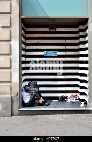 London, England, UK. Homeless man in a fire exit doorway in the Strand Stock Photo