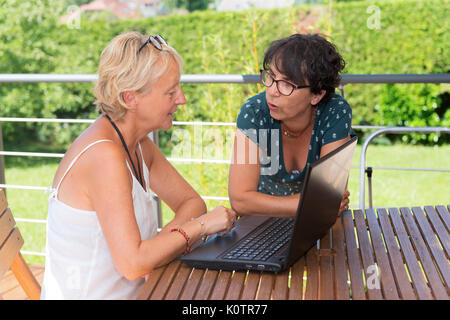 two mature women friends using a laptop, outdoors Stock Photo