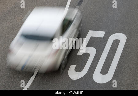 A car driving over a sign indicating a speed limit of 50 km/h painted on the asphalt near Tubingen, Germany, 25 August 2017. The speed limit of 50 km/h in villages and towns was introduced 60 years ago. Photo: Sebastian Gollnow/dpa Stock Photo