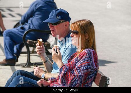 Lyme Regis, Dorset, UK. 25th August 2017.  UK Weather.  Holidaymakers enjoying an ice cream in the warm sunshine at the seaside resort of Lyme Regis in Dorset on the friday before the August bank holiday.   Photo Credit: Graham Hunt/Alamy Live News Stock Photo