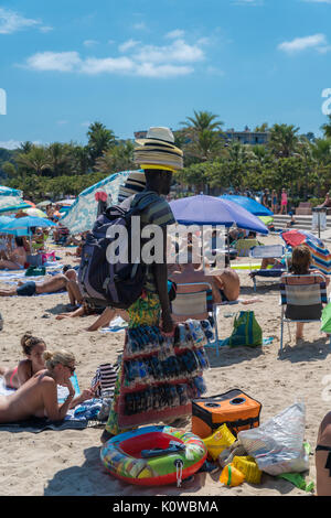 An African man sells straw hats on the beach in Antibes, France Stock Photo