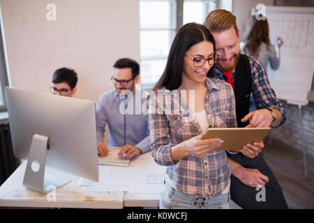 Young attractive designers talking and looking at digital tablet Stock Photo