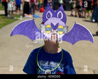 A young boy wears a mask with protective glasses as he watches a total solar eclipse at Museum of Aviation August 21, 2017 in Warner Robins, Georgia. The total eclipse swept across a narrow portion of the contiguous United States from Oregon to South Carolina and a partial solar eclipse was visible across the entire North American continent along with parts of South America, Africa, and Europe. Stock Photo