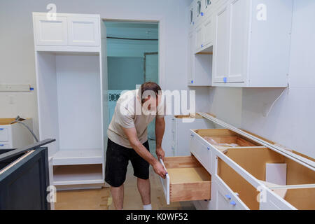 Installation kitchen. Worker installs doors to kitchen cabinet. Stock Photo