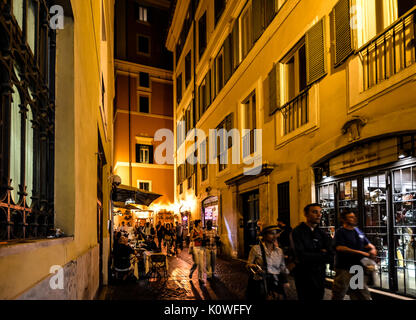 A evening stroll in Rome Italy through a narrow back street with an outdoor cafe and tourists enjoying themselves Stock Photo