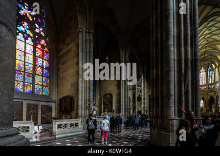 The beautiful gothic interior of St Vitus Cathedral in Prague as tourists and worshipers enjoy the stained glass windows and architecture Stock Photo