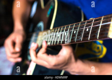 blurred background of a guy wearing blue T-shirt playing his guitar Stock Photo