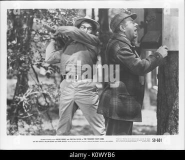 A movie still scene from 'The Tougher They Come' (1950 Columbia Pictures film), showing a man about to clobber another who is making a call on a public phone, 1950. Stock Photo