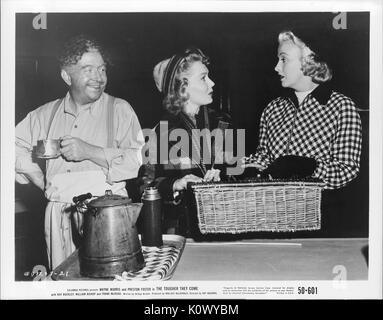 A movie still scene from 'The Tougher They Come' (1950 Columbia Pictures film), showing three adults, two women and a man, with the two ladies calmly arguing on something while holding on to a picnic basket, and the man beside the lady in the middle laughingly listening to them, 1950. Stock Photo