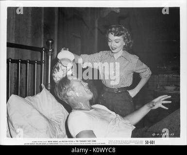 A movie still scene from 'The Tougher They Come' (1950 Columbia Pictures film), showing a young woman happily pouring water from a pitcher on a man's head while he is lying in bed, 1951. Stock Photo