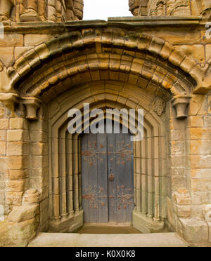 Arched door with ornate hinges surrounded by series of decorative stone arches at historic Tynemouth priory ruins, England Stock Photo