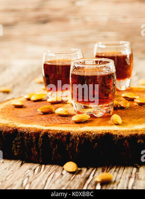 Italian liqueur Amaretto in cups with almonds on a wooden table, selective focus Stock Photo