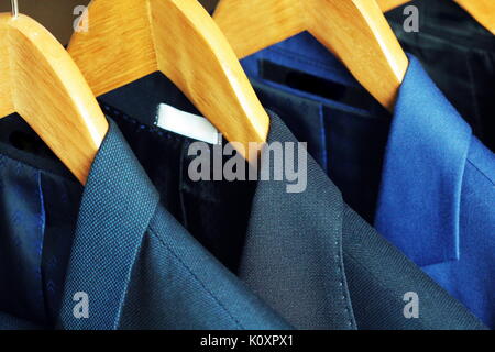 Row of men's suits hanging on rack for sale Stock Photo