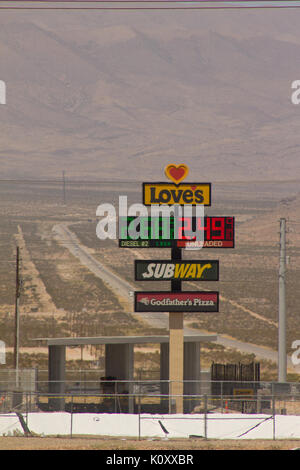 A fuel station sign in front of a long desert road near Las Vegas, Nevada Stock Photo