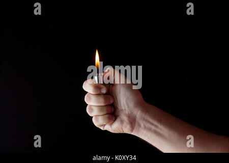 hand holding a lighter in a dark atmosphere Stock Photo
