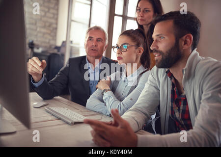 Business workers in discussion at computer in office Stock Photo