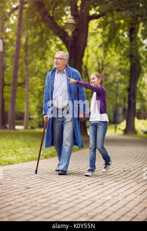 Young granddaughter showing something in the park disabled senior grandfather Stock Photo