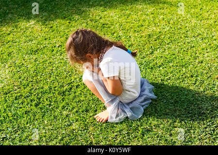 A young girl having a tantrum and crying on the lawn Stock Photo