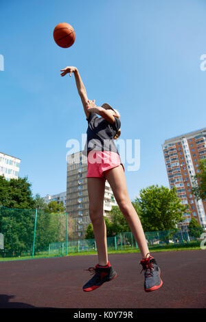 Girl basketball player throws the ball up Stock Photo