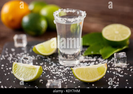 Mexican tequila in short glasses with salt, lime slices and ice on wooden table Stock Photo