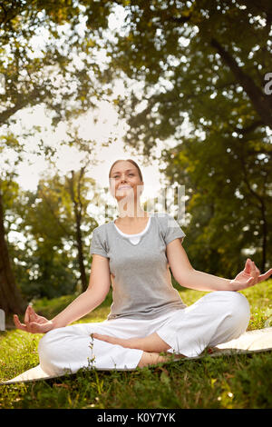 Nice female meditate in lotus pose in forest Stock Photo