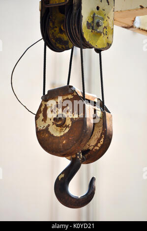 Lifting hook attached to sheave suspended by wire rope from boom of crane Stock Photo